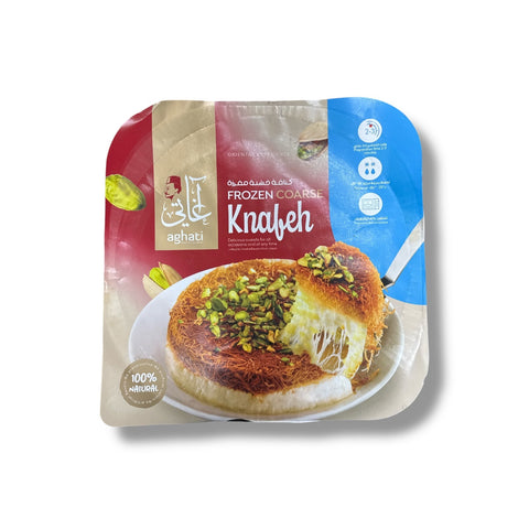 Packaged frozen coarse Naabulsi Knafeh dessert topped with pistachios and melted cheese on a plate.