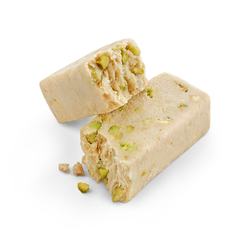 Close-up of halva with pistachio, showcasing the crumbly texture and visible pieces of pistachio nuts, on a white background.
