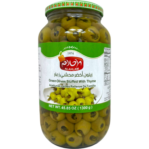 Alahlam green olives, stuffed thyme, presented in an elegant glass jar.