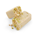 Close-up of halva with pistachio, showcasing the crumbly texture and visible pieces of pistachio nuts, on a white background.