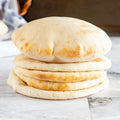 Stack of Albasha Fresh Baked Pita Bread, soft and chewy, on a marble surface