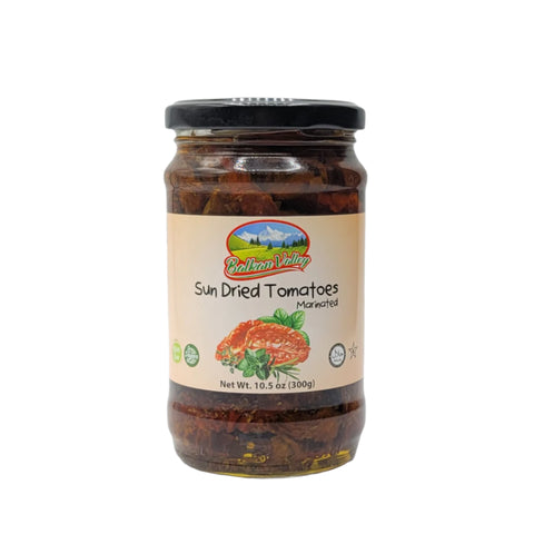 Balkan Valley Marinated Sun Dried Tomatoes in a jar, showcasing the product label with a scenic mountain background, highlighting that it weighs 10.5 oz (300g). The jar contains marinated, sun-dried tomatoes with associated natural ingredients.